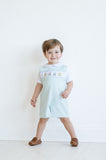 In his smocked mint green jonjon, a little boy shines with timeless style, perfect for photos and sweet moments.