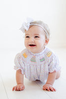 A baby girl looks adorable in the smocked sprinkle birthday cake bubble, perfect for her special celebration.