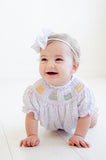 A baby girl looks adorable in the smocked sprinkle birthday cake bubble, perfect for her special celebration.