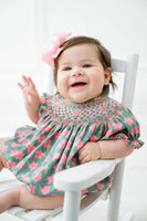 A little girl wearing the pink and green azalea smocked birdie bubble celebrates spring with timeless charm.