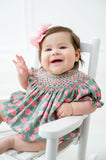 A little girl wearing the pink and green azalea smocked birdie bubble celebrates spring with timeless charm.