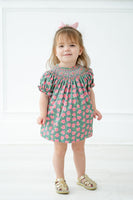 The pink and green smocked bloomer set includes coordinating bloomers that add a playful, whimsical touch.