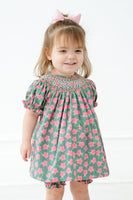 A little girl wearing the pink and green smocked bloomer set celebrates The Masters with timeless charm.