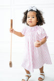 A little girl wearing the Pink Smocked Golf Dress looks absolutely charming with the playful pink golf carts on the smocked bodice.