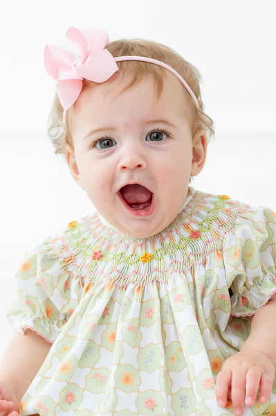 
A little toddler girl wearing the Smocked Wildflower Bubble will be ready to bloom this spring with its charming light green and white checkered pattern.