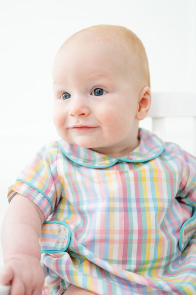 A baby boy wearing the Colorful Plaid Alexander Bubble looks adorable in its vibrant, spring-inspired plaid pattern.