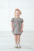 A little girl wearing the pink and green smocked bloomer set looks radiant at any spring celebration.