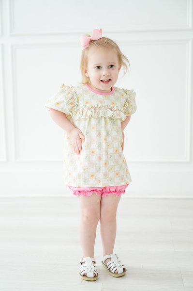 A little girl wearing the Pima Wildflower Bloomer Set will look sweet and stylish with its light green and white checkered pattern paired with colorful wildflowers.