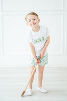 A little boy wearing the Green Smocked T-Shirt and Short Set stands out with the adorable green golf cart design on his shirt, perfect for a day on the course.