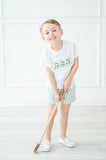 A little boy wearing the Green Smocked T-Shirt and Short Set stands out with the adorable green golf cart design on his shirt, perfect for a day on the course.