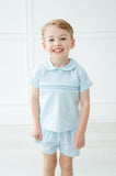 The Classic Blue Shirt and Short Set for boys features hand-smocked detailing for a polished, timeless look.