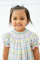 The Pastel Smocked Easter Plaid Dress for young girls features hand-smocked flowers and geometric details, creating a timeless, heirloom-quality design.