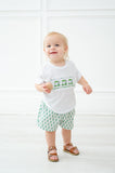 A toddler boy wearing the Green Smocked T-Shirt and Short Set looks adorable with the playful green golf cart design on the smocked shirt.