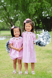 Two girls wearing matching pink gingham smocked football outfits