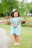 Girl standing outdoors on path wearing Smocked Fall Gourds Dress by Ruth and Ralph with white hair bow