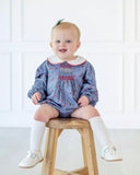 little girl sitting in blue floral bubble with smocking on chest.