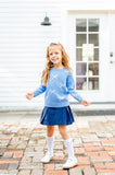 Girl dancing in blue sweater with white bows.