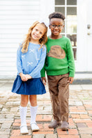 Girl standing with boy wearing blue bows sweater.