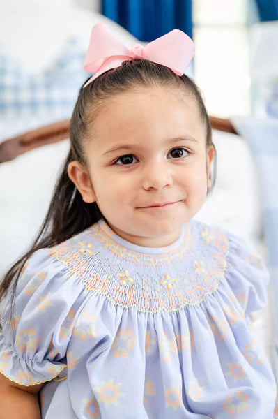 girl wearing blue, orange and yellow smocked dress