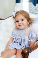 girl wearing blue, orange and yellow smocked bloomer set