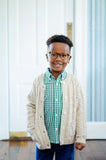 boy wearing green shirt and oatmeal colored cable knit cardigan.