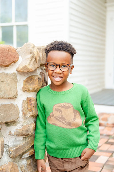 boy wearing green sweater with cowboy hat on it.