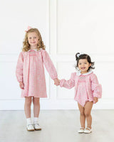 Girls wearing smocked pink floral dress and bubble