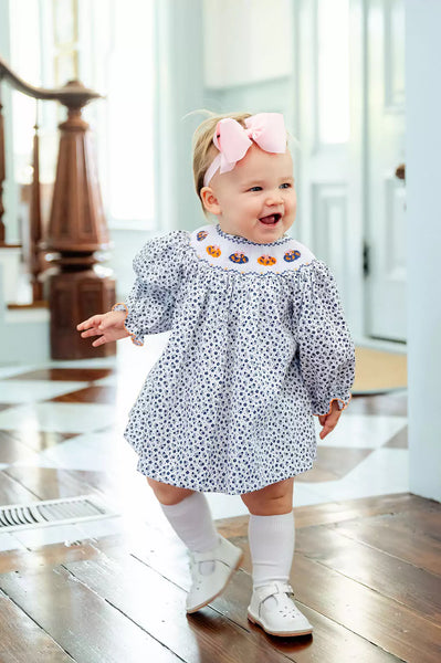 girl wearing smocked floral and pumpkins bloomer set