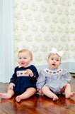 boy and girl wearing smocked pumpkin outfits