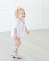 Toddler girl wearing pink hand embroidered cowgirl boots layette set.